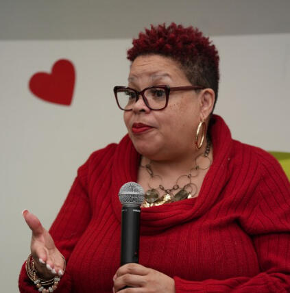 April speaking into a microphone at a live event